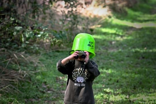 child with a bucket on their head. normal is the illusion