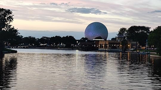 EPCOT's Spaceship Earth in the distance behind a lake of glimmering water at dusk