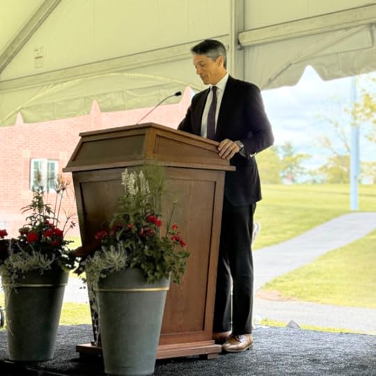 Peter in a suit and tie standing at a podium