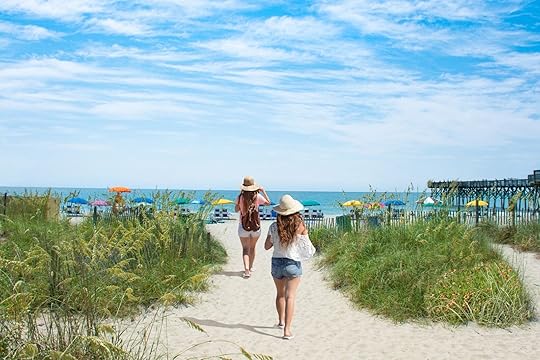 Girls walking on the beach on summer vacation. Beach chairs and parasols on beautiful white sand in the background. Myrtle Beach, South Carolina