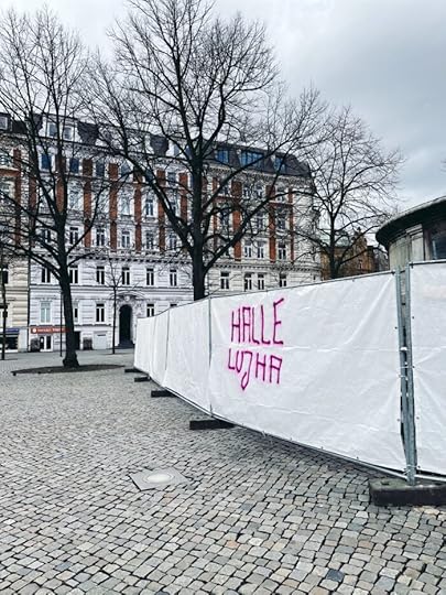 Ein mit weißer Folie bespannter Bauzaun, auf den jemand in pinkfarbener Schrift 