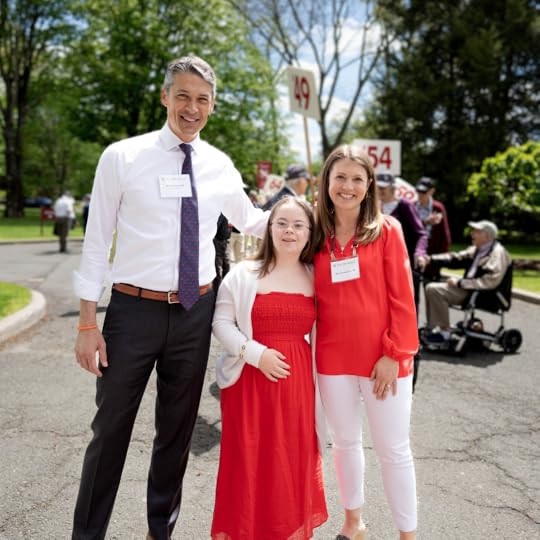 Peter, Penny, and Amy Julia standing next to each other in front of a crowd gathered for a parade
