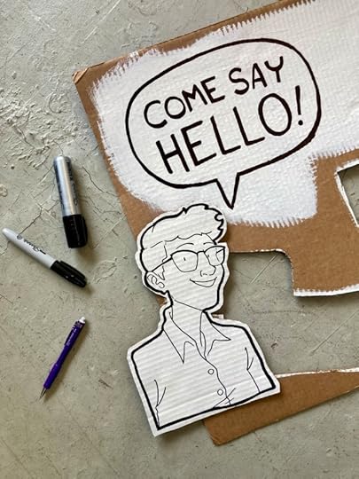 A black and white line drawing on cardboard of Lucy, a young white woman with glasses and short hair. A word balloon by her head says "come say hello!"