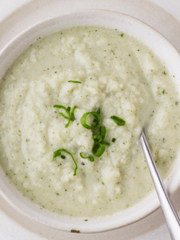 Cauliflower Goat Cheese Soup in a white bowl ready to be served on a plate.