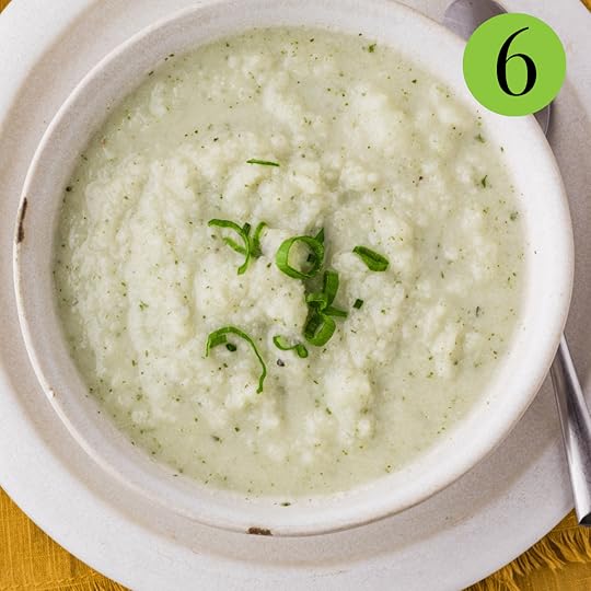 Cauliflower Goat Cheese Soup served on a white bowl and plate with parsley.
