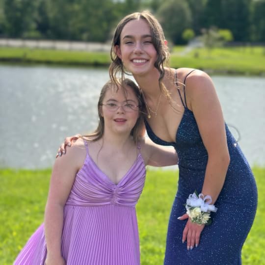 an outdoor photo of Penny wearing a purple prom dress and posing with a friend in front of a pond