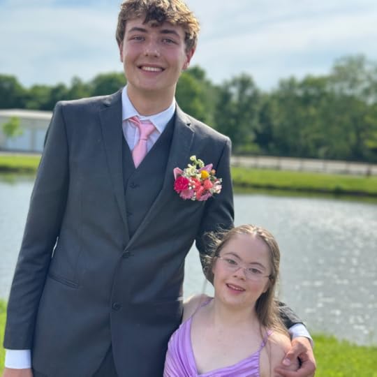 an outdoor photo of Penny wearing a purple prom dress and posing with a friend in front of a pond