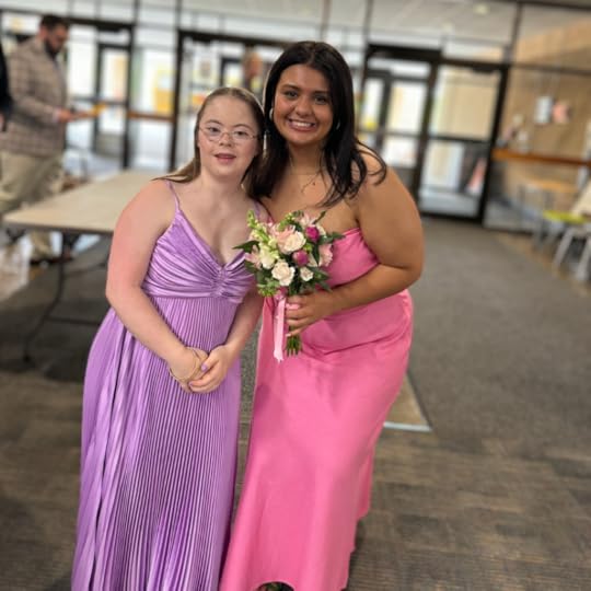 an indoor photo of Penny wearing a purple prom dress and posing with a friend