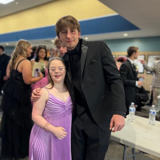 an indoor photo of Penny wearing a purple prom dress and posing with a friend