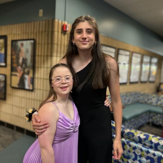 an indoor photo of Penny wearing a purple prom dress and posing with a friend