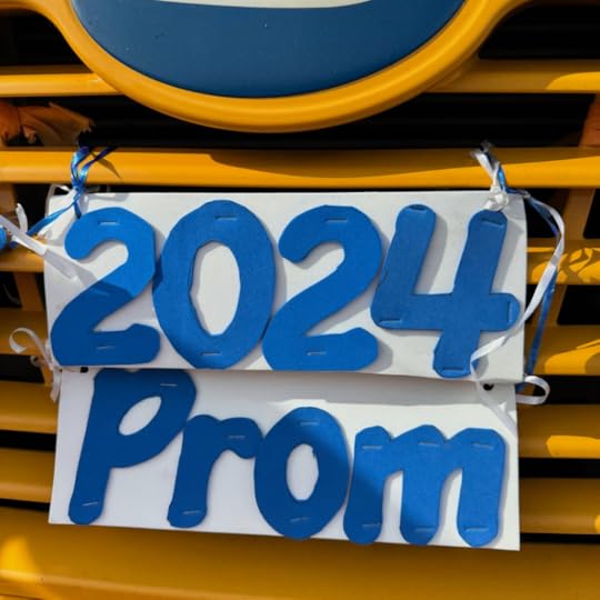 front grill of a yellow school bus with a white sign attached that says 