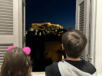 Two children looking through window at Acropolis, Athens, at night