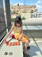 Child playing card game at Acropolis Museum, Athens, view of Acropolis behind her