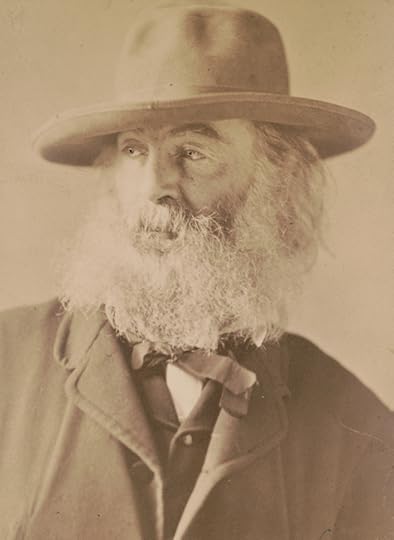 Walt Whitman, head-and-shoulders portrait, facing left, wearing hat. He has a bushy white beard and is wearing a suit coat and vest. 