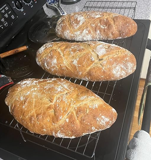 Three loaves of manoomin bread fresh out of the oven on cooling racks. Where did the fourth one go?