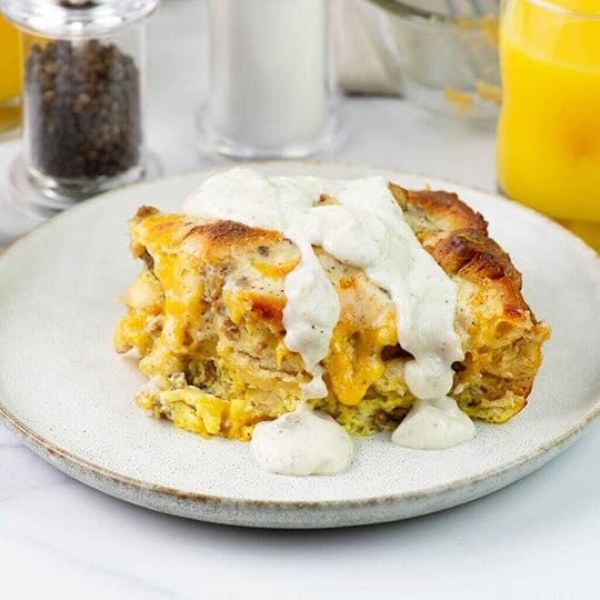 A square serving piece of biscuits and gravy casserole with gravy drizzled over the top on a plate.