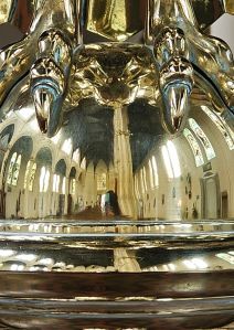 Picture of the insides of a church reflected in the brass dome at the bottom of the lectern.