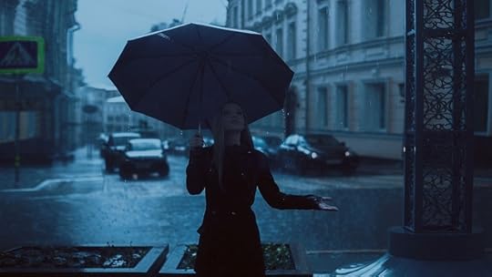 Blonde woman holding an umbreella on a murky, rainy city street