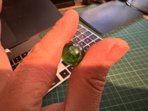 A picture of a silvery green marble about the size of a marrowfat pea