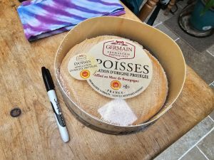 A picture of an extremely large, runny, rinse-washed cheese in a wooden box.