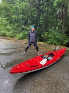 man with red kayak in a parking lot in the rain