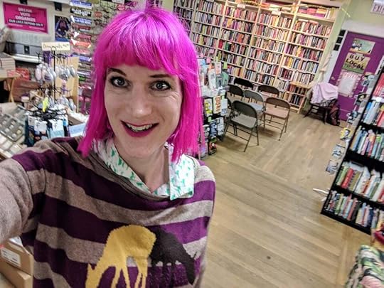 A selfie I took back in 2019 when I was getting ready to do a reading at a Barnes and Noble in Philadelphia... we filled all those chairs! I've got neon bright pink hair and I'm wearing a stripey sweater with deers on it.