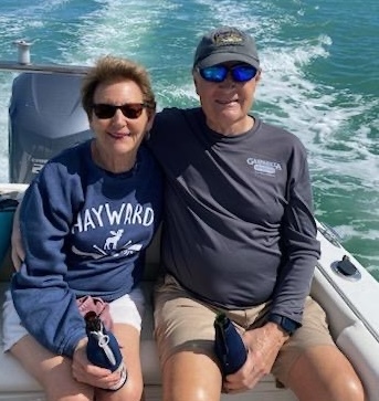A man and a woman sitting in the back of a speedboat cruising in a lake