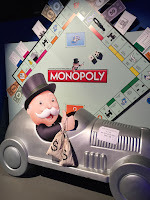 Large Monopoly and old man with bags of money driving car