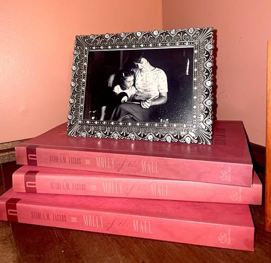 Three copies of Molly of the Mall, with a framed photo of a mother and child reading