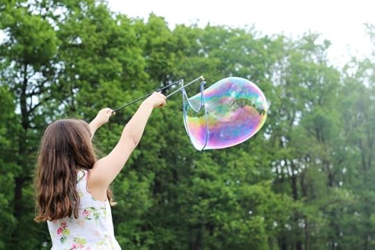 child creating a giant bubble. the meaning of life is to live