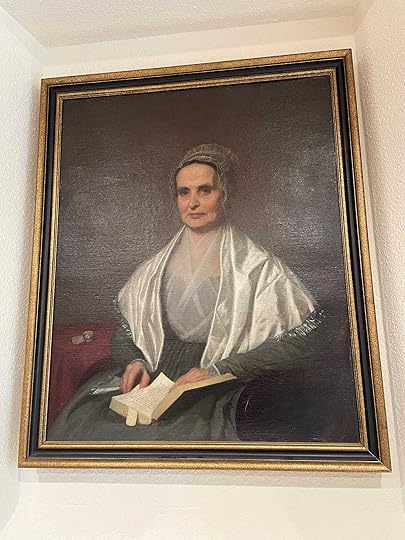 Mott 3/4 seated portrait, wearing a bonnet and white shawl over a dark dress, book open in her lap.