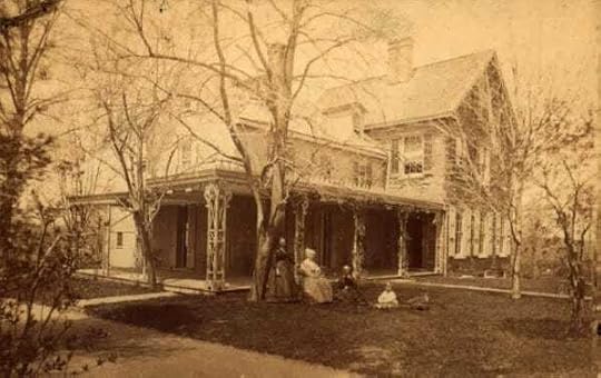 Sepia image of two-story house with large porch; four figures are on the lawn, next to a tree. 
