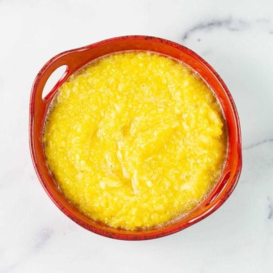 Overhead image of crushed pineapple in a red bowl.