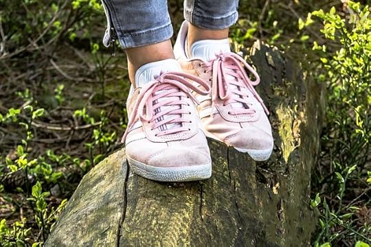 Closeup of pale pink sneakers balancing on a log
