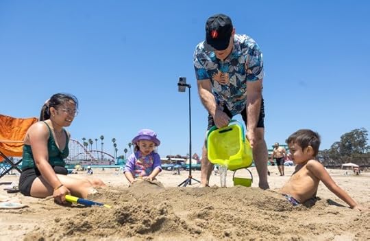 Escaping triple-digit heat at their home in Fairfield, Rhea Banks watches as her husband Jim pours cool ocean water on their children Elaina and Ethan, buried in the sand, Wednesday, July 3, 2024, at the Boardwalk beach in Santa Cruz, Calif. The couple wanted to stay an extra night but couldn't find a room in town. (Karl Mondon/ Bay Area News Group)