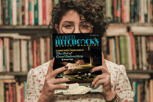 Woman holding up July/August issue of Alfred Hitchcock's Mystery Magazine