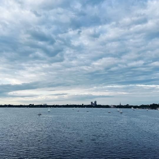 Blick von der Kennedybrücke auf die Außenalster unter blaugrau verhangenem Himmel. Einige Segelboote, im Hintergrund die Mundsburghochhäuser.