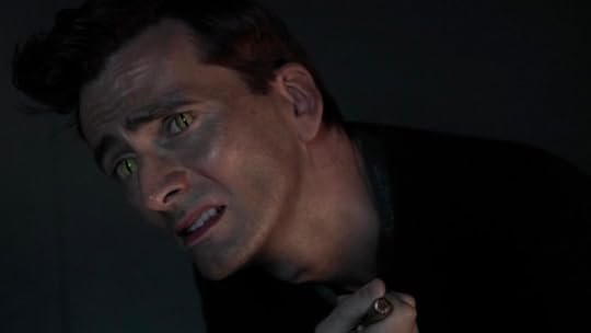 A picture with a black background. Crowley, leaning on the chair in his flat, raises his head to speak to God. He looks very distressed.