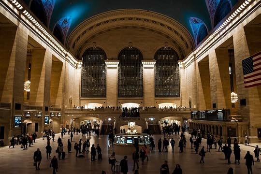 Interior Grand Central Station, NYC, with the central kiosk, lots of people, and grand architecture.
