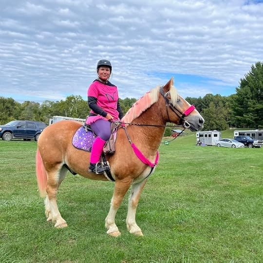 lady dressed in pink sits on a proud palomino horse