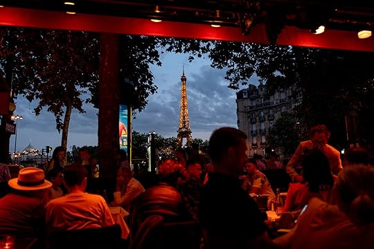 The Eiffel Tower is illuminated as diners sit in a cafe ahead of the 2024 Summer Olympics, Friday, July 19, 2024, in Paris. (AP Photo/David Goldman)