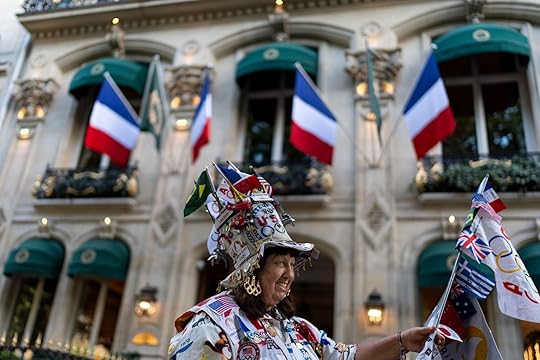 Vivianne Robinson, of Los Angeles, shows the flag pole she carries with all the countries who have hosted an Olympics as she stops to talk to people on the street while walking through Paris ahead at the 2024 Summer Olympics, Saturday, July 20, 2024. This will be Robinson's seventh Olympics she will have attended in person. (AP Photo/David Goldman)