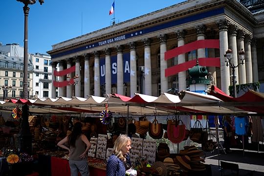 People shop at an open-air market in front of Team USA House, Friday, July 19, 2024, in Paris, France. Team USA House is set up at the former Paris stock exchange and will offer activities and a base to cheer on and celebrate Team USA at the Olympic Games. (AP Photo/David Goldman)