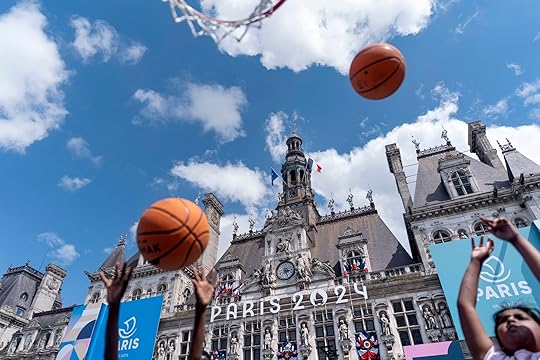 The Hotel de Ville, or town hall, is decorated for the 2024 Summer Olympics as children shoot basketballs at a fan zone set on the square, Sunday, July 21, 2024, in Paris. France. (AP Photo/David Goldman)