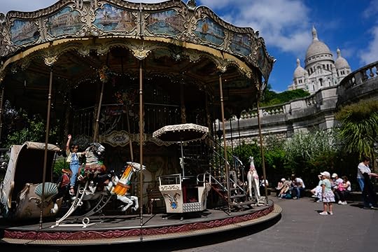 A child rides a carousel near Sacre Coeur of Montmartre Basilica, ahead of the 2024 Summer Olympics, Monday, July 22, 2024, in Paris, France. (AP Photo/Rebecca Blackwell)