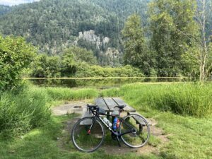 Road bike leaning against a picnic table with a backdrop of river and trees