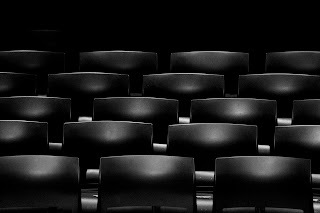 Image of rows of movie theater seats, black in color