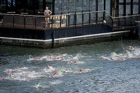 A woman watches athletes competing during the swim leg of...