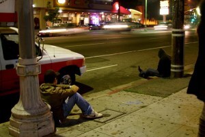 guys sitting on curb by grungy street