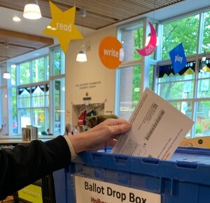 Hand inserting ballot in ballot box